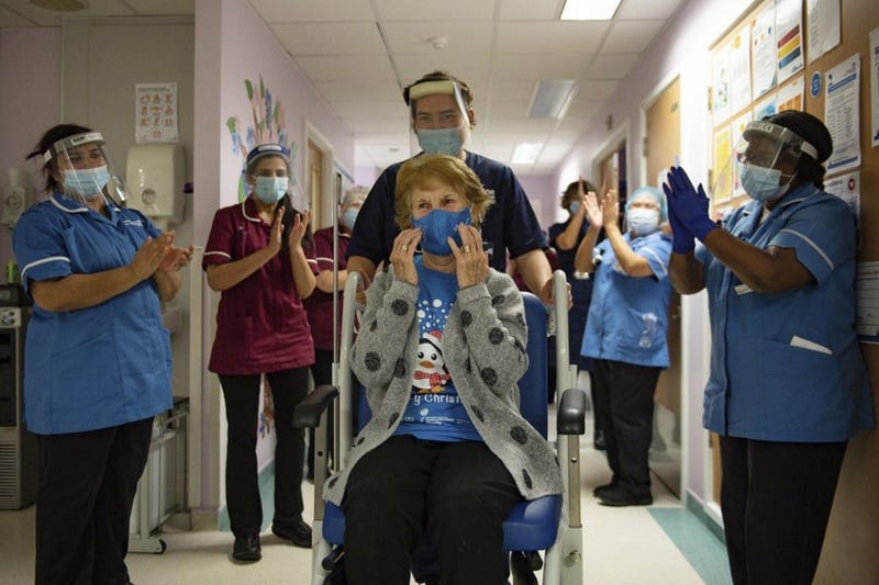 Margaret Keenan, 90, is applauded by staff as she returns to her ward after becoming the first patient in the UK to receive the Pfizer-BioNTech COVID-19 vaccine, at University Hospital, Coventry, England, Tuesday Dec. 8, 2020. 