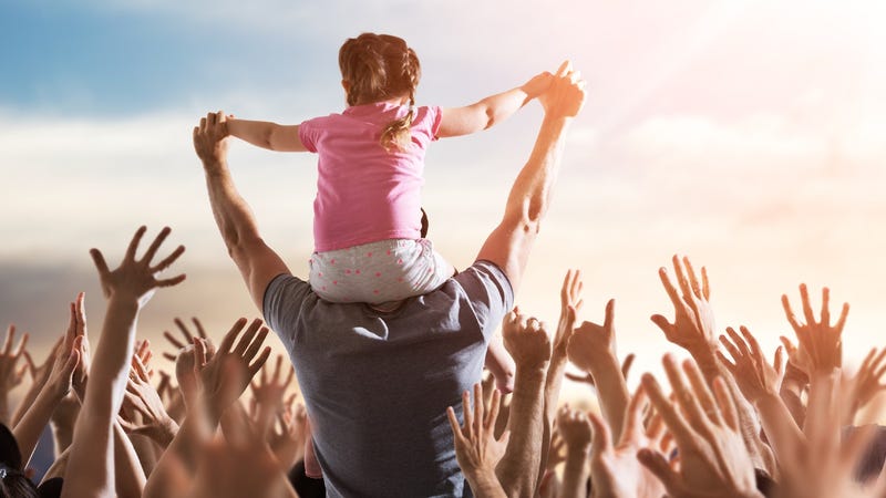 Little girl on her dad's shoulders at an outdoor concert