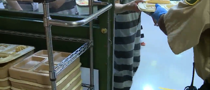 Inmates in the Clay County Jail receive trays of food at meal time