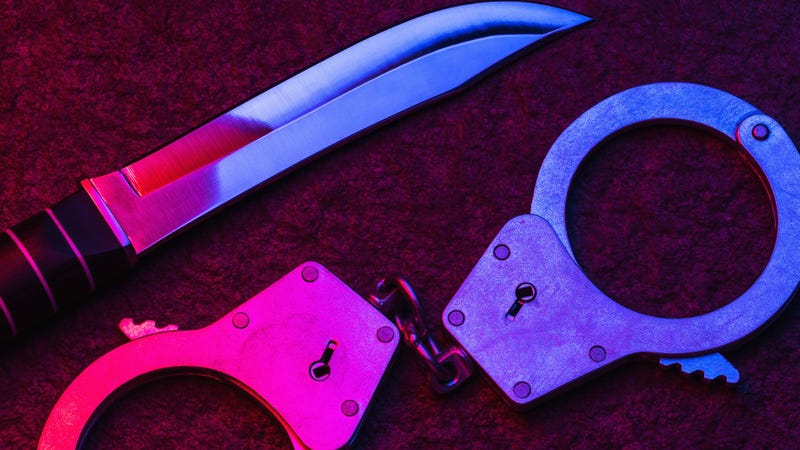 Handcuffs and a knife illuminated by the flashing lights of a police car - stock photo