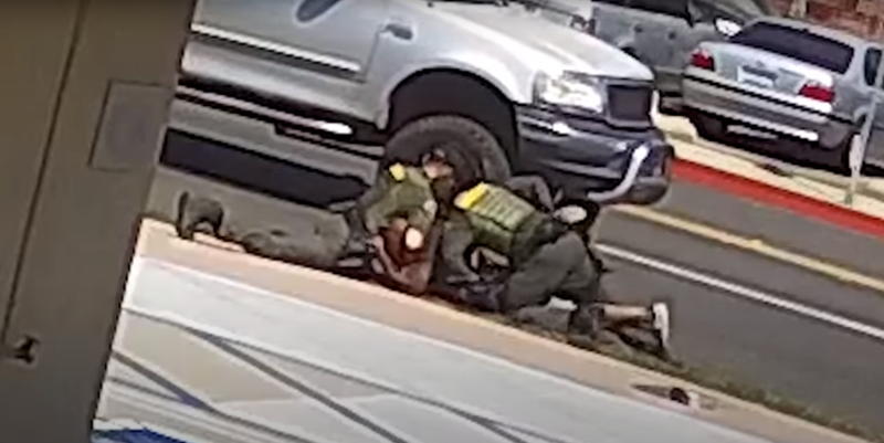 man being wrestled to the ground on the side of the road by two sheriff's deputies