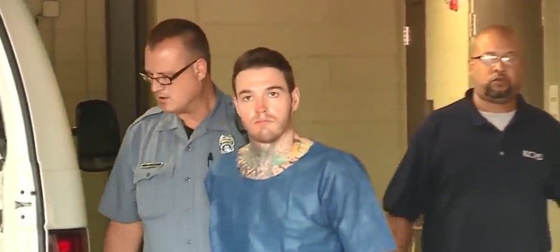 Kylr Yust in handcuffs, being led to a jail transport van