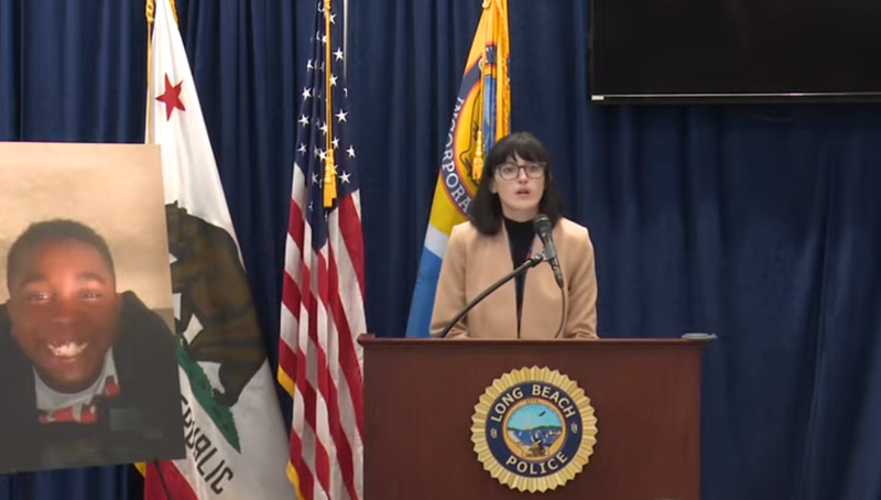 woman speaks at podium next to photo of child
