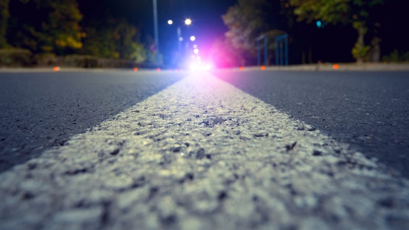 Focus on city road with blurred police car red and blue lights in the distance