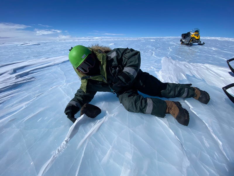 researcher in winter gear next to black rock