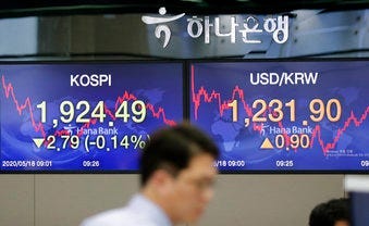 A currency trader walks near the screens showing the Korea Composite Stock Price Index (KOSPI), left, and the foreign exchange rate between U.S. dollar and South Korean won at the foreign exchange dealing room in Seoul, South Korea. (AP Photo/Lee Jin-man)