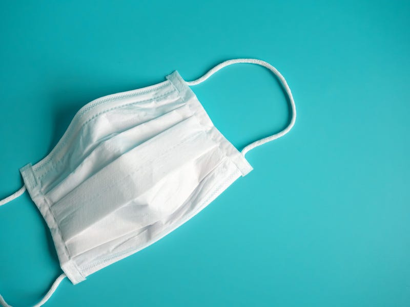 close up white surgical face mask on blue green background