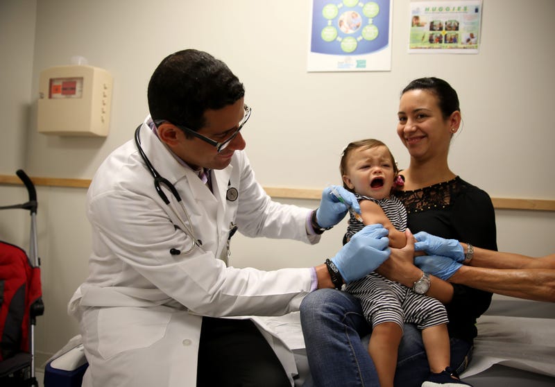 aniela Chavarriaga holds her daughter, Emma Chavarriaga, as pediatrician Jose Rosa-Olivares, M.D. administers a measles vaccination during a visit to the Miami Children's Hospital on June 02, 2014 in Miami, Florida.