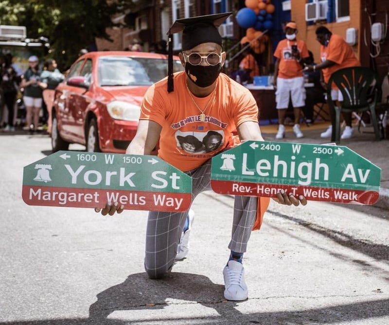Melchezedek "Mel" Wells, president of addiction recovery nonprofit One Day at a Time, holds street signs honoring his parents, who co-founded the organization.