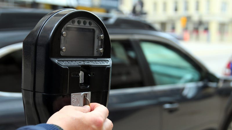 Man paying by coins at a parking meter - stock photo