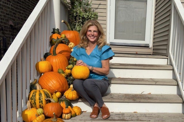 Jodi Richman sits on porch steps with pumpkins
