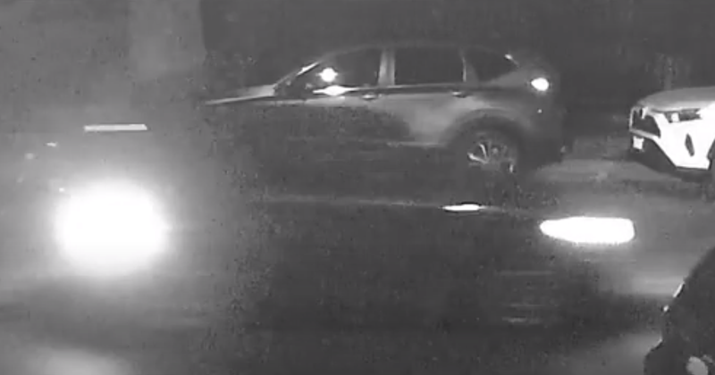 blurry black-and-white security video of a speeding car