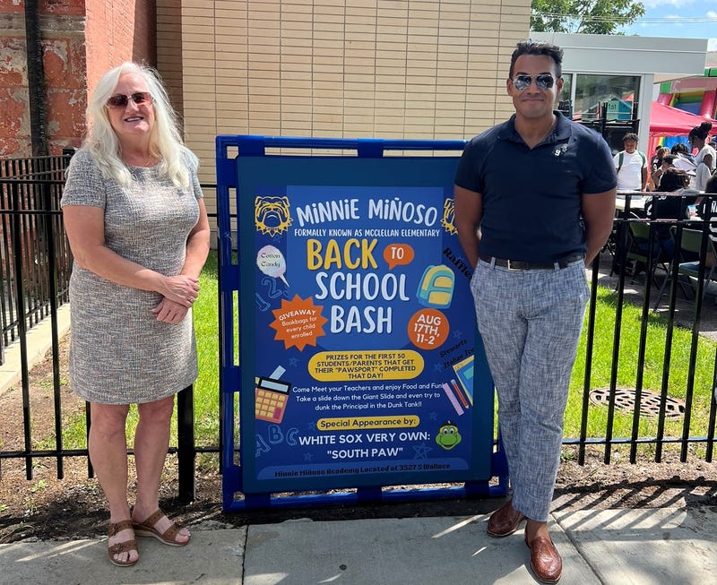 Minnie Miñoso's widow and son standing next to sign