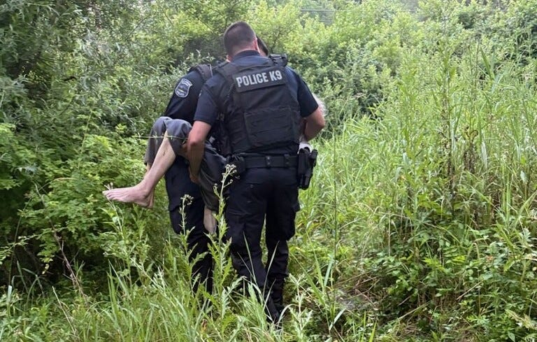 Officers are seen carrying the missing man after he was found in a creek.