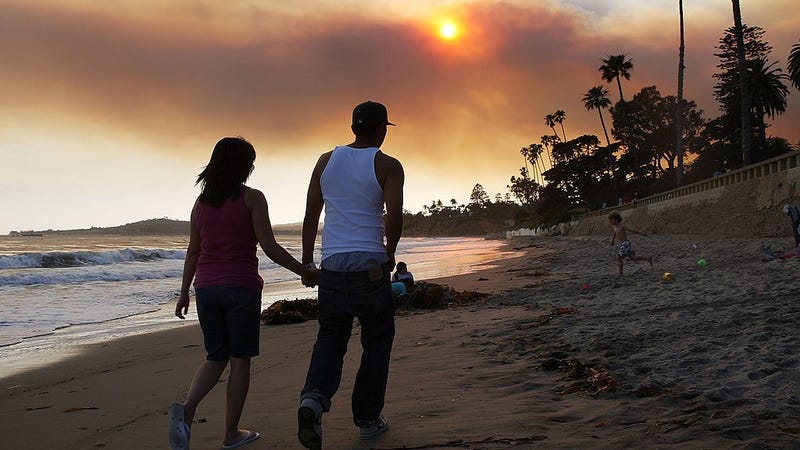 A couple walks along the sand under heavy smoke from the Jesusita fire at Butterfly Beach on May 7, 2009 in Montecito, just south of Santa Barbara, California. 