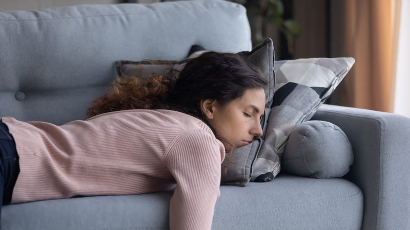 Tired young woman sleeping on couch at home - stock photo