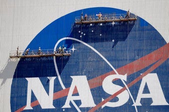 Workers near the top of the 526 ft. Vehicle Assembly Building at the Kennedy Space Center spruce up the NASA logo standing on scaffolds in Cape Canaveral, Fla., Wednesday, May 20, 2020. (AP Photo/John Raoux)
