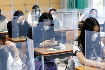 Senior students wait for class to begin with plastic boards placed on their desks at Jeonmin High School in Daejeon, South Korea, Wednesday, May 20, 2020. (Kim Jun-beom/Yonhap via AP)