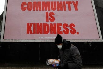 A man wearing a mask to help stop the spread of the coronavirus passes advertising display. (AP Photo/Kirsty Wigglesworth)