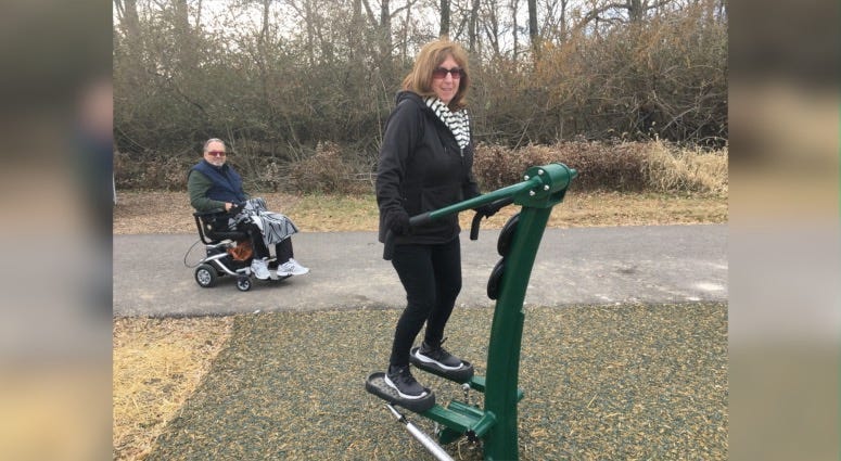 Pam Kleb tries out the adjustable stepper while her husband Rick watches from his motorized wheelchair.