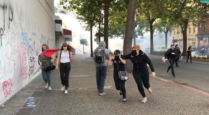 Protestors run as tear gas is deployed in Oakland, 6-1-20
