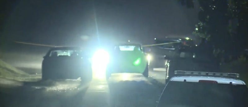 Crime scene tape and police vehicles on residential street at night