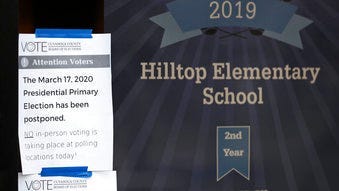A sign is taped to the entrance of a polling location at Hilltop Elementary School, Tuesday, March 17, 2020, in Beachwood, Ohio. (AP Photo/Tony Dejak)