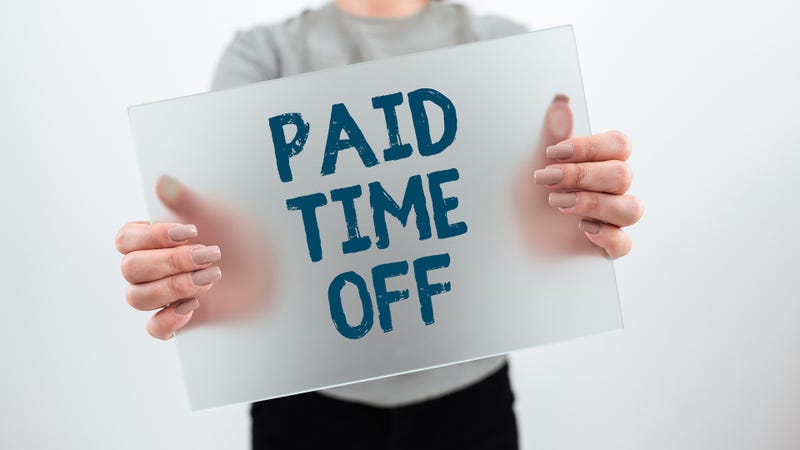 Person holding sign reading "Paid Time Off"