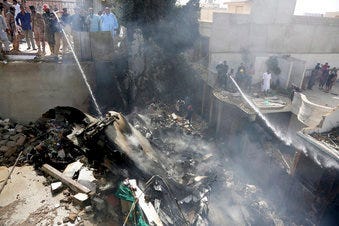 Fire brigade staff try to put out fire caused by plane crash in Karachi, Pakistan, Friday, May 22, 2020. (AP Photo/Fareed Khan)