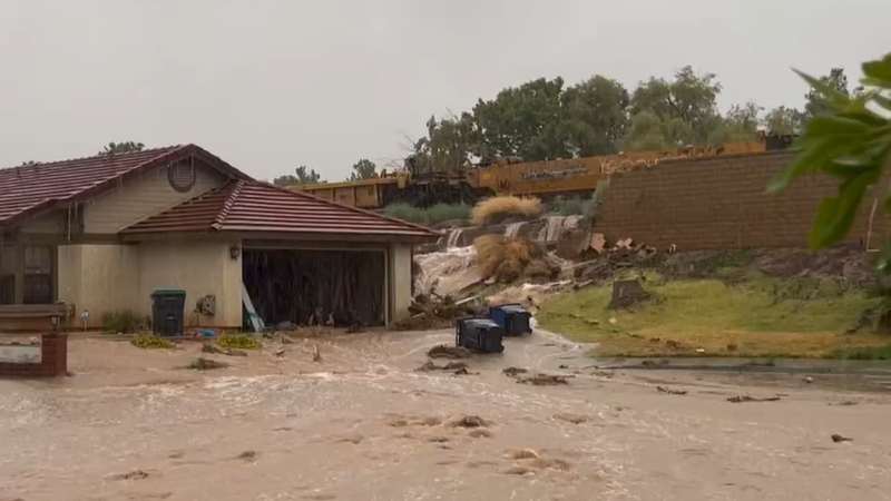 home with driveway and road covered in mud and a broken retaining wall behind it