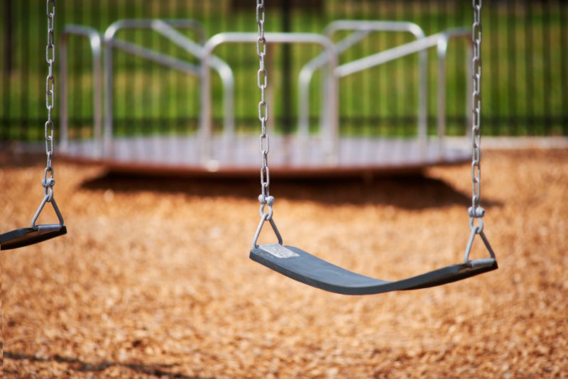 A solo shot of a swing with a merry-go-round in the background