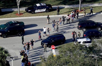FILE - In this Wednesday, Feb. 14, 2018, file photo, students hold their hands in the air as they are evacuated by police from Marjory Stoneman Douglas High School in Parkland, Fla. (Mike Stocker/South Florida Sun-Sentinel via AP, File)