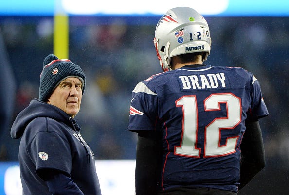 Bill Belichick glares behind him during a conversation with Tom Brady. 