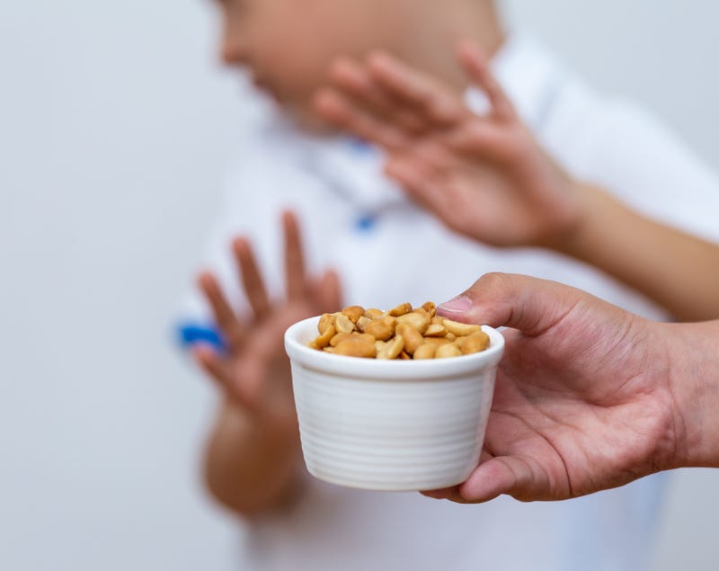 peanut allergy illustration; kid holding up hands with dish of nuts in foreground