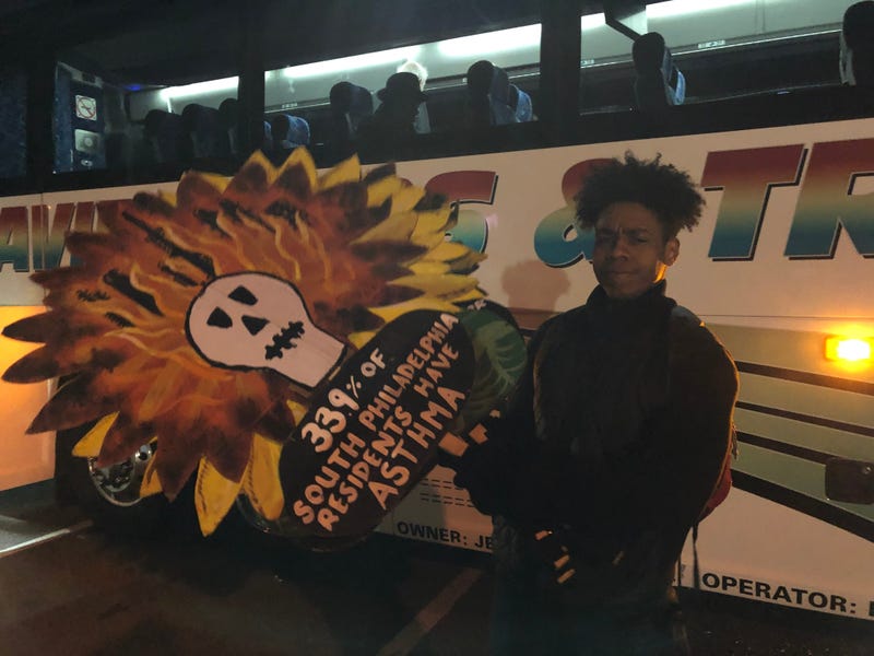 A community activist poses with signs to be used at a protest in New York City, where the PES action will occur.
