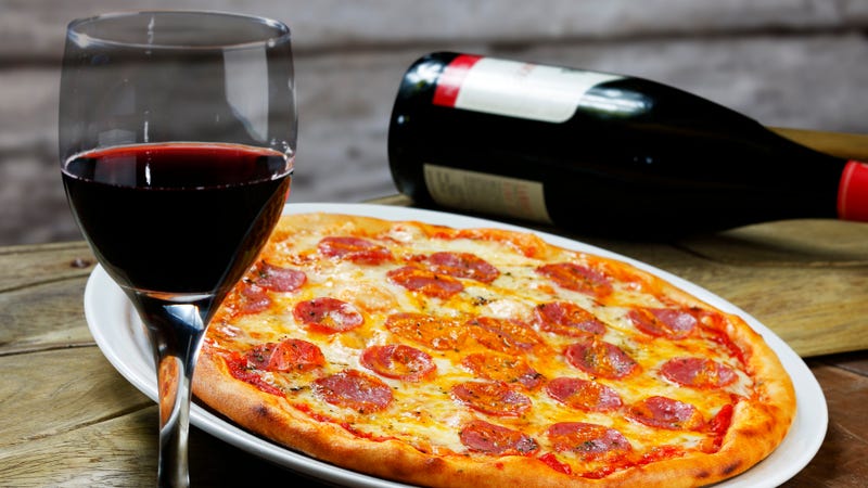A glass of wine and a pepperoni pizza