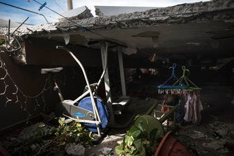 A stationary bike stands where the roof collapsed next to a home's game room located on the second floor, which is the top floor, after an earthquake hit Guanica, Puerto Rico. (AP Photo/Carlos Giusti)