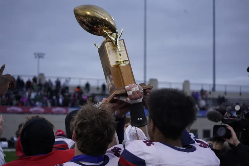 St. Rita football players hoist the Prep Bowl trophy after topping Kenwood Academy 21-7 in Chicago's 2023 Prep Bowl.