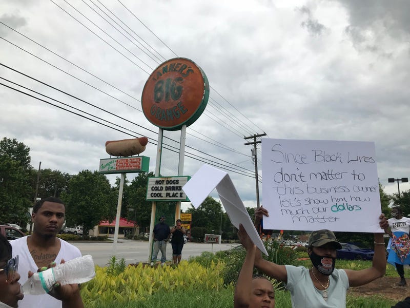 Protesters Hold Signs In Front of Tanner's
