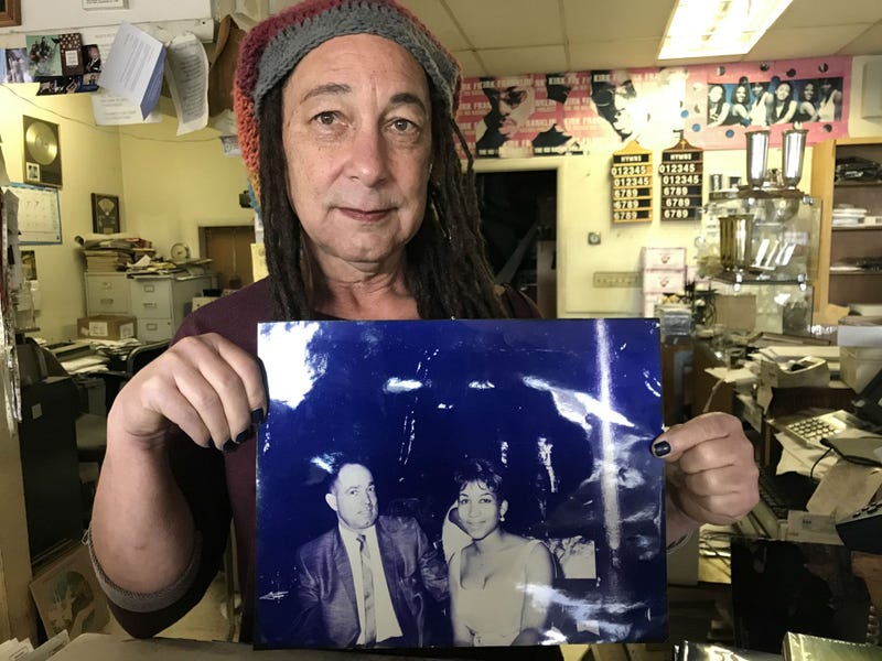 Store owner Diara Reid with a photo of her dad with then 17-year old Aretha Franklin, who he brought to Oakland for a gospel concert
