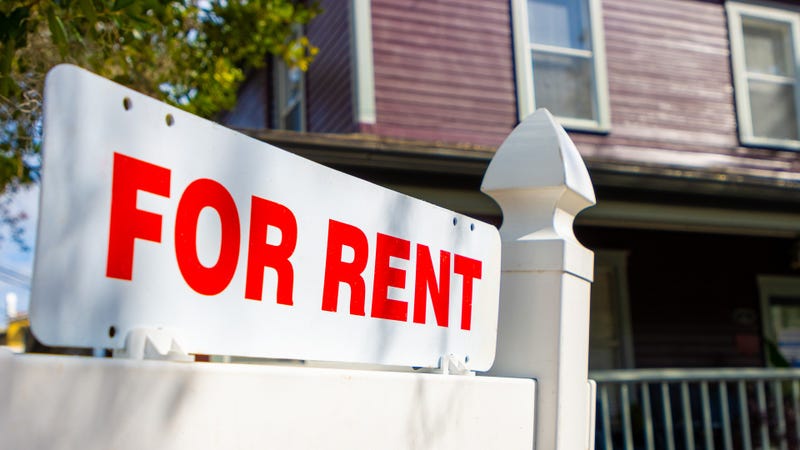 A white and red sign advertises a house for rent