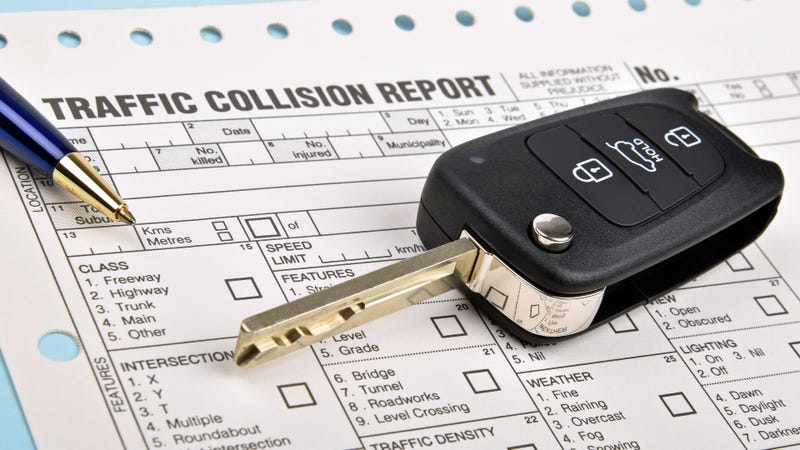 black car key with a traffic collision report and blue pen
