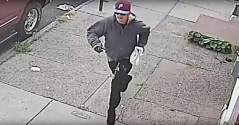 Robbery suspect wearing gloves, sunglasses and a burgundy Phillies cap.