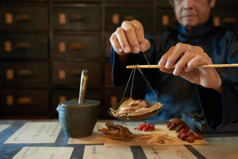 A man measures ingredients in traditional Asian apothecary.