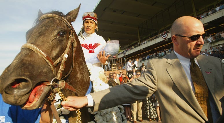 Sarava with jockey Edgar Prado is led to the winners' circle by trainer Kenneth McPeek after winning the 134th Belmont Stakes at Belmont Race Park on June 8, 2002.