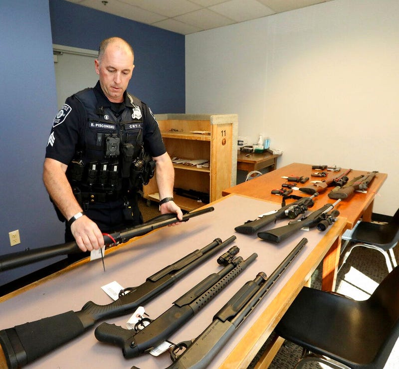 In this May 23, 2018, photo, Seattle Police Crisis Response Team Sgt. Eric Pisconski displays guns seized from people deemed to be a danger to themselves or others.