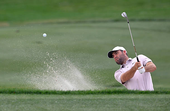 Scottie Scheffler hits a shot out of a bunker.