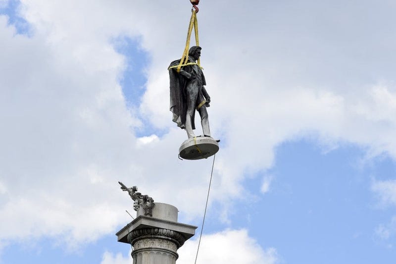 The statue of former U.S. vice president and slavery advocate John C. Calhoun hovers above its monument after contractors completed a 17-hour removal process on Wednesday, June 24, 2020.