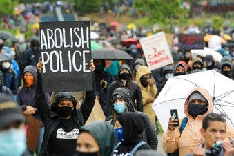 A protester holds a sign that reads "Abolish Police" during a "Silent March" against racial inequality and police brutality that was organized by Black Lives Matter Seattle-King County, Friday, June 12, 2020, in Seattle. (AP Photo/Ted S. Warren)