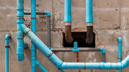 FILE: Blue water plastic pipes on the concrete wall in the condominium building.